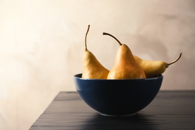 Photo of Bowl with ripe pears on table against grey background