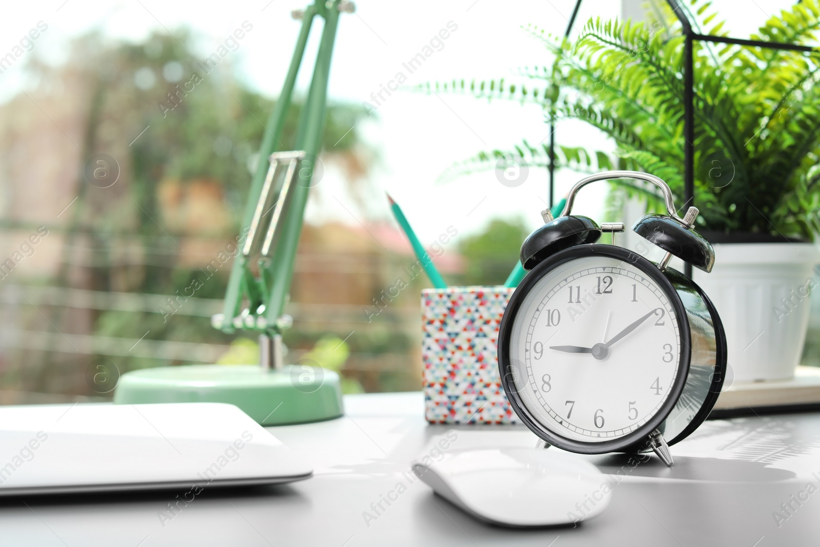 Photo of Alarm clock on table in office. Time to work