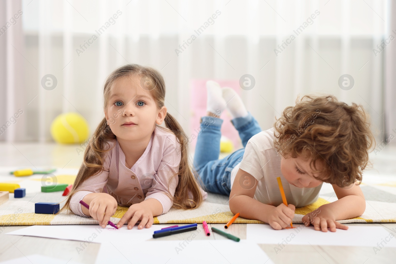 Photo of Cute little children drawing on floor in kindergarten