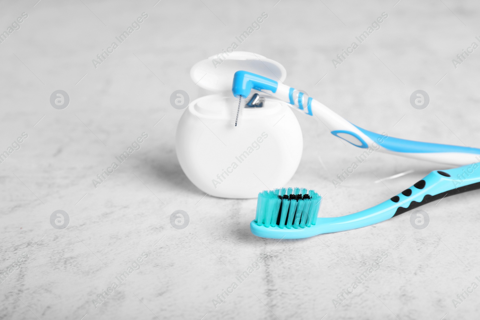 Photo of Container with dental floss and toothbrushes on light grey textured table