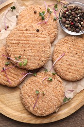 Tasty vegan cutlets with breadcrumbs and spices on wooden board, top view