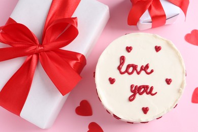 Photo of Bento cake with text Love You, gift boxes and paper hearts on pink table, flat lay. St. Valentine's day surprise