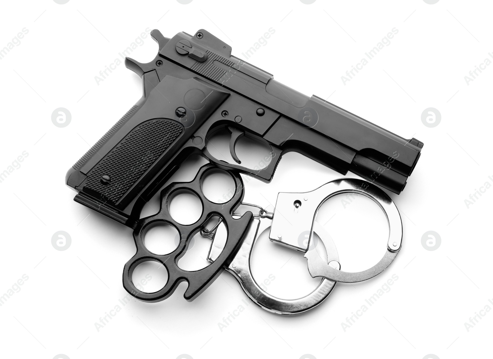 Photo of Black brass knuckles, gun and handcuffs on white background, top view