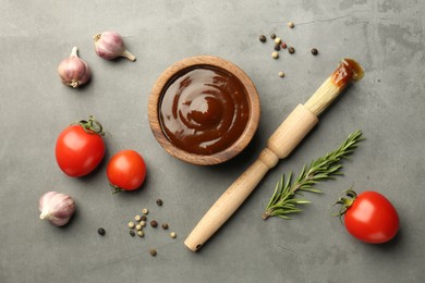 Photo of Flat lay composition with tasty barbeque sauce in bowl on grey textured table