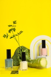 Photo of Stylish presentation of beautiful nail polishes in bottles on yellow background