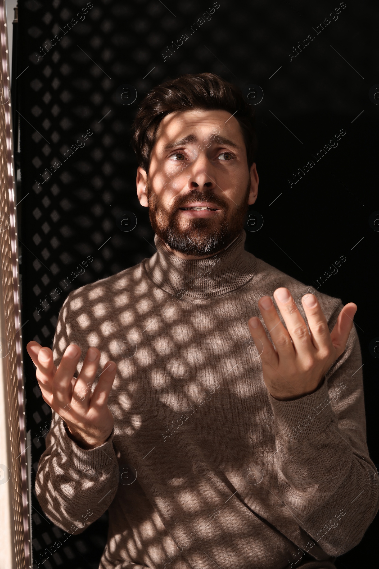 Photo of Upset man talking to priest during confession in booth