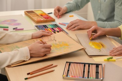 Artists drawing with soft pastels and pencils at table, closeup