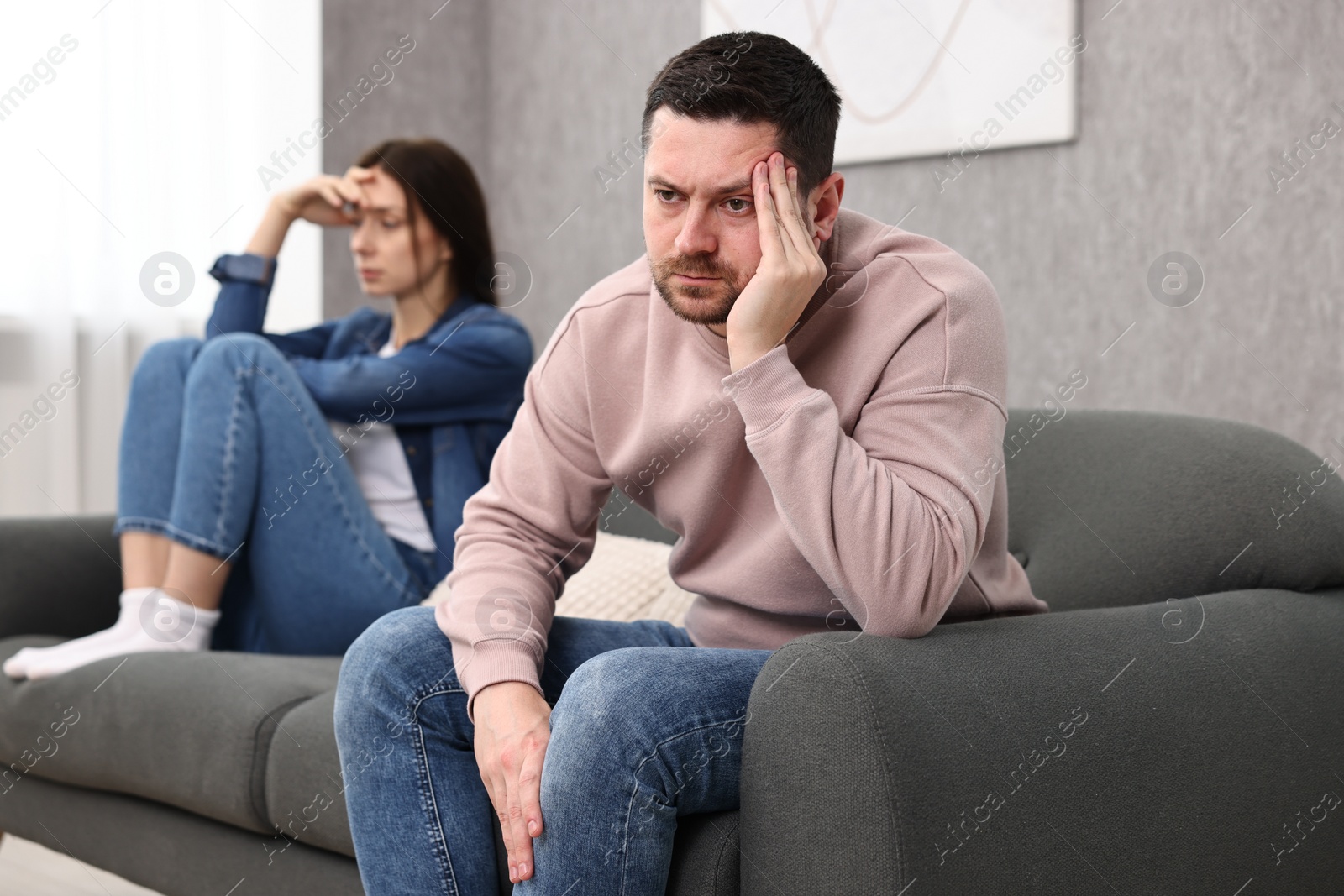 Photo of Offended couple ignoring each other after quarrel indoors, selective focus. Relationship problems