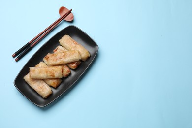 Photo of Fried spring rolls served on light blue table, top view. Space for text
