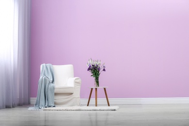 Photo of Stylish comfortable armchair near color wall