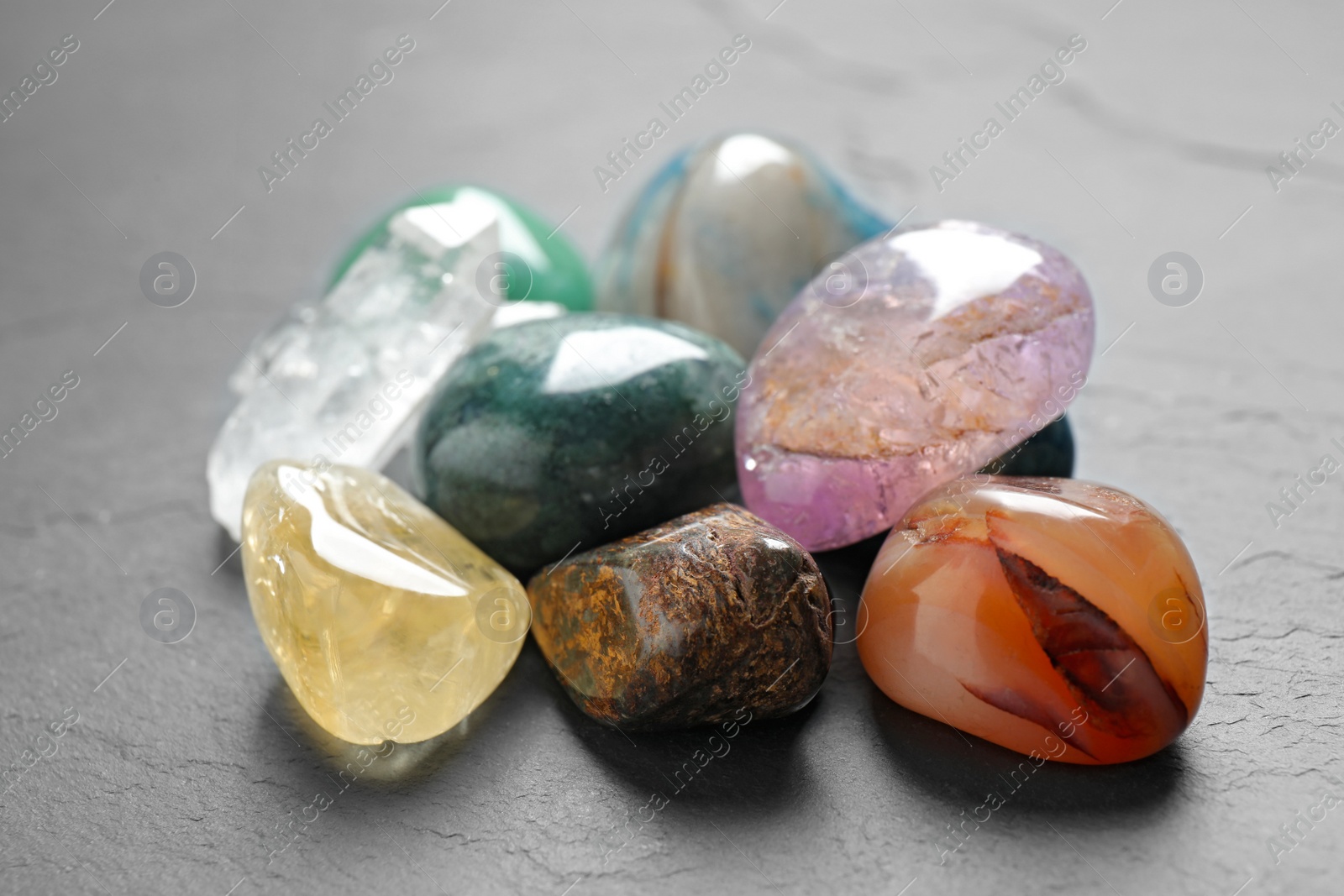 Photo of Pile of different beautiful gemstones on grey background