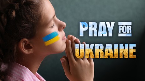 Image of Pray for Ukraine. Little girl with drawn Ukrainian flag on cheek and phrase