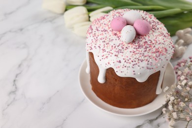 Tasty Easter cake with decorative sugar eggs and flowers on white marble table. Space for text