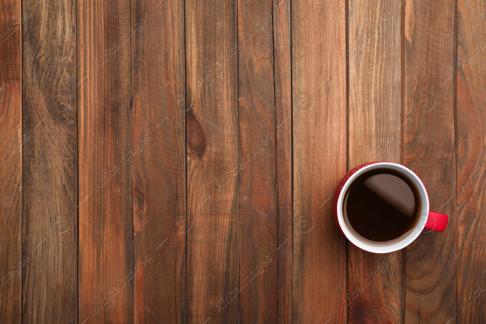 Photo of Ceramic cup with hot aromatic coffee on wooden background, top view
