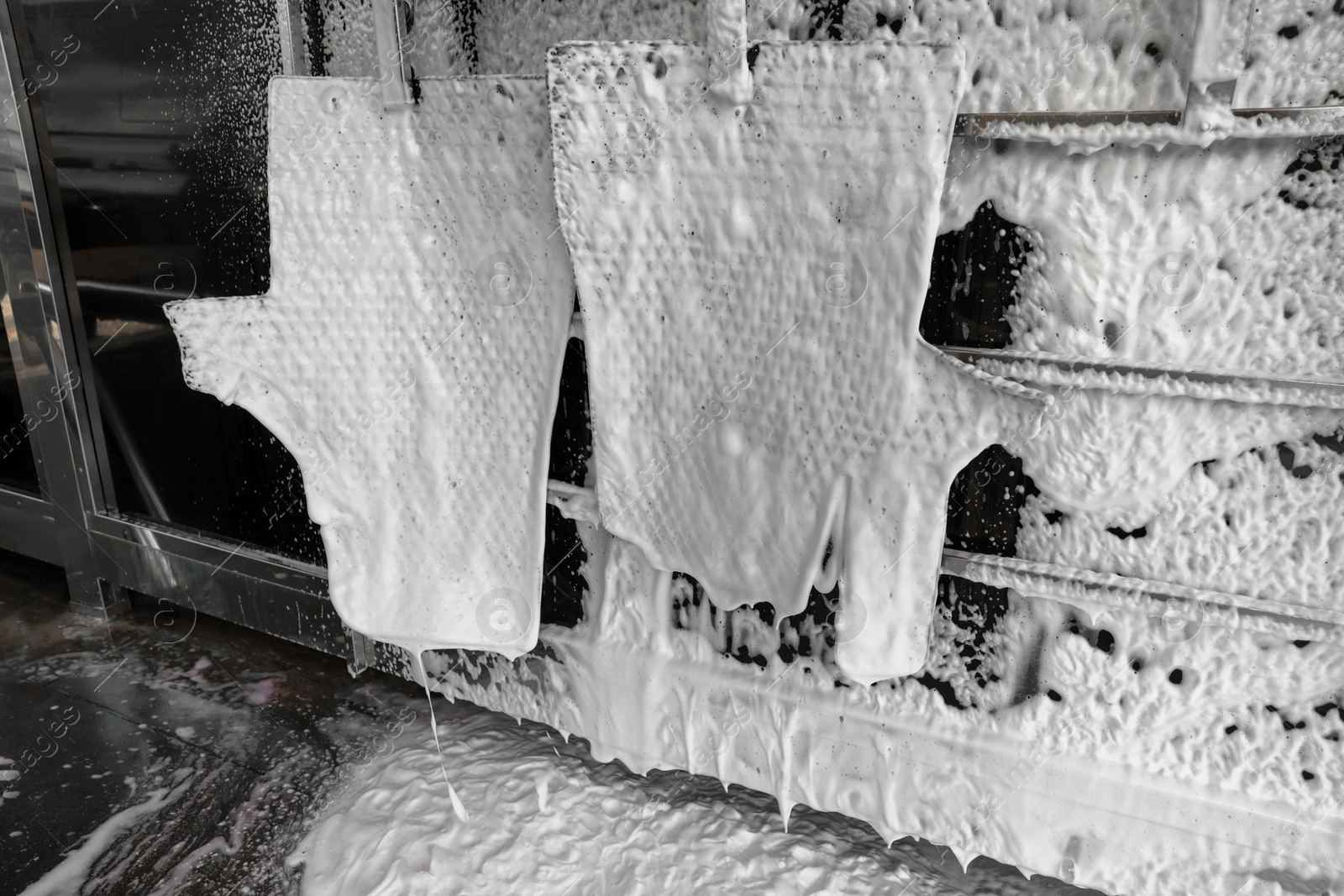 Photo of Auto mats covered with foam hanging at car wash, closeup