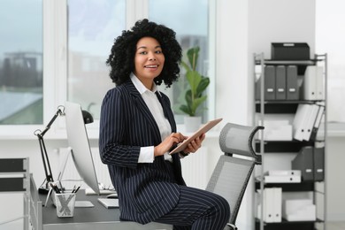 Photo of Smiling young businesswoman using tablet in office
