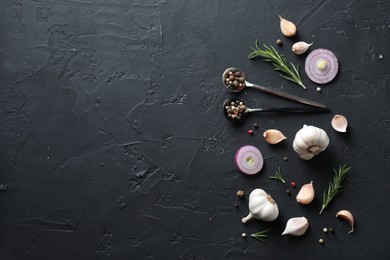 Fresh raw garlic, onion rings and spices on black table, flat lay. Space for text