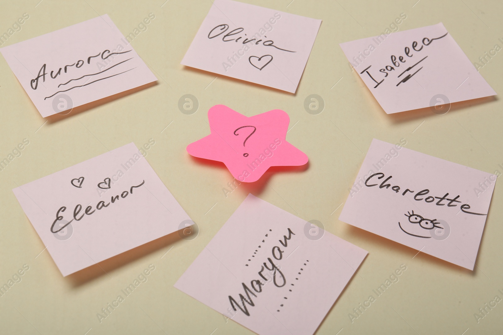 Photo of Choosing baby name. Paper stickers with different names and question mark on beige background