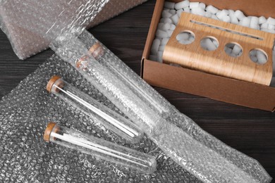 Test tubes with bubble wrap and cardboard box on dark wooden table