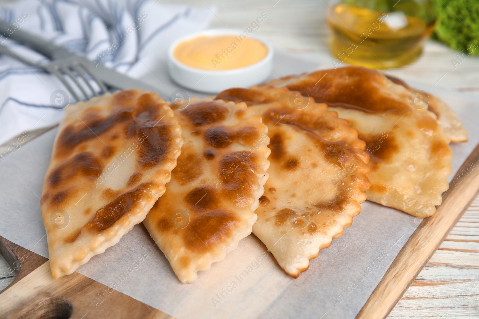 Photo of Delicious fried chebureki on white wooden table