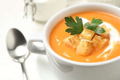 Photo of Delicious pumpkin soup served on white table, closeup