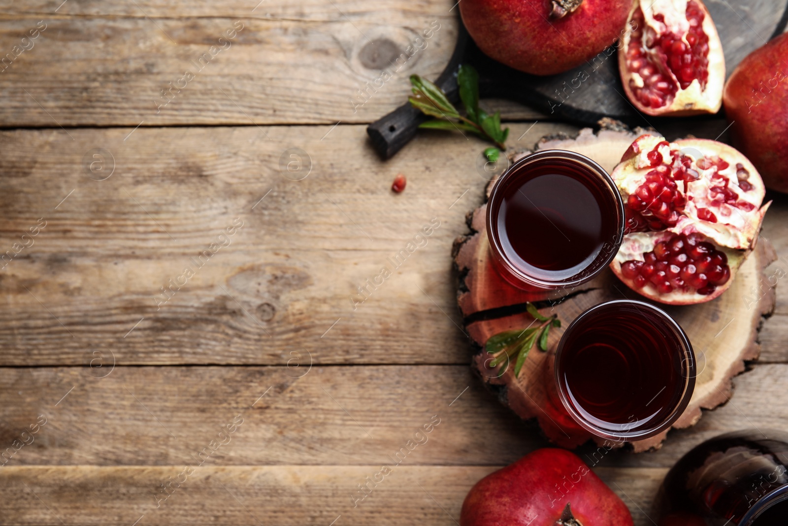 Photo of Pomegranate juice and fresh fruits on wooden table, flat lay. Space for text