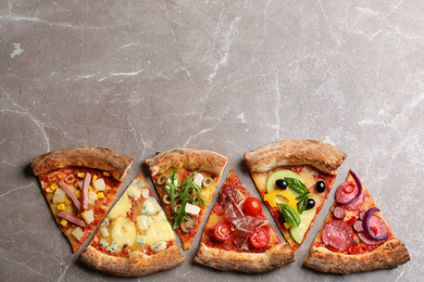 Slices of different delicious pizzas on grey marble table, flat lay. Space for text
