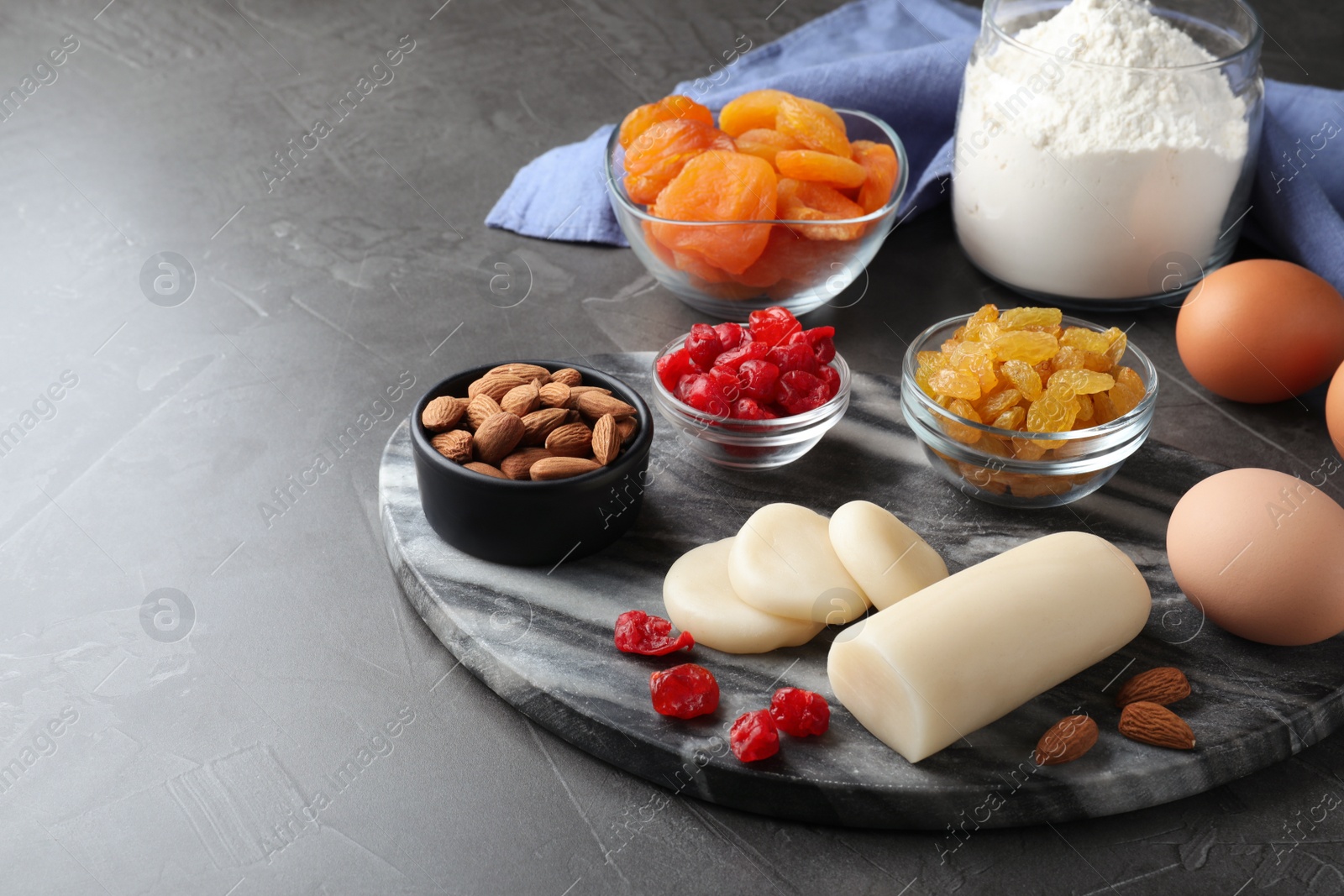 Photo of Marzipan and other ingredients for homemade Stollen on grey table. Baking traditional German Christmas bread