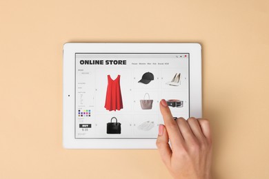 Photo of Woman with tablet shopping online on beige background, top view