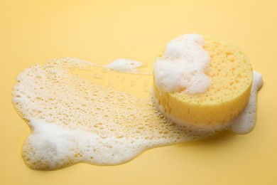 Photo of Sponge with foam on yellow background. Space for text