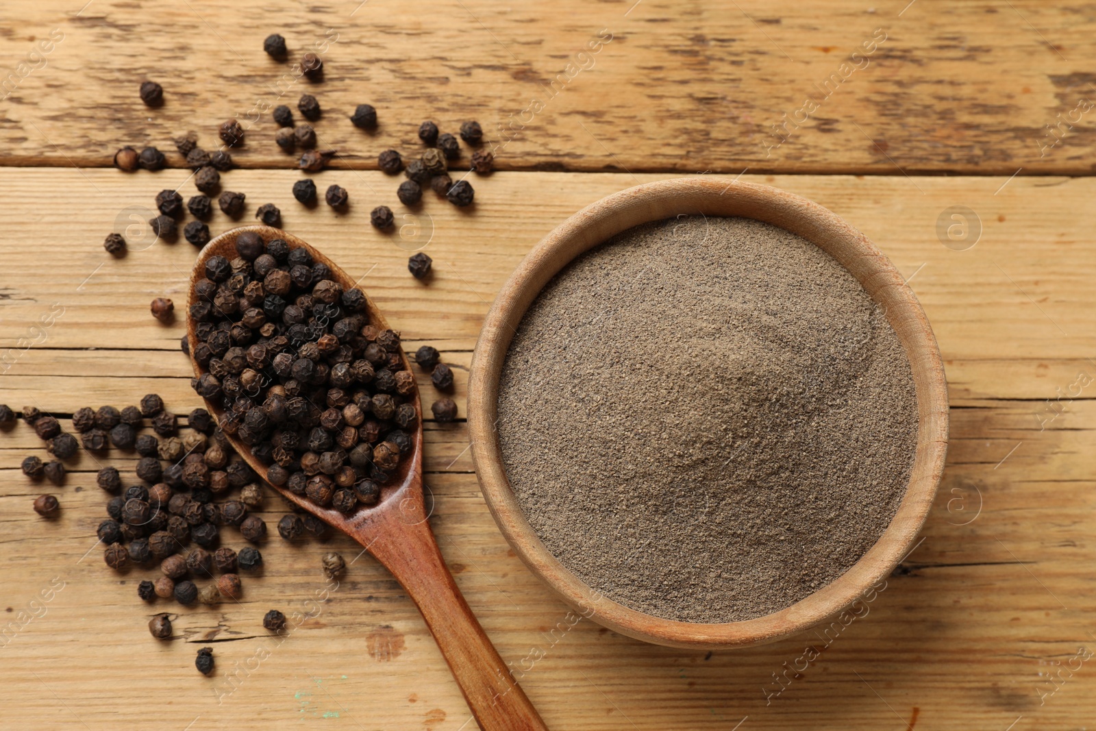 Photo of Aromatic spice. Ground and whole black pepper on wooden table, top view