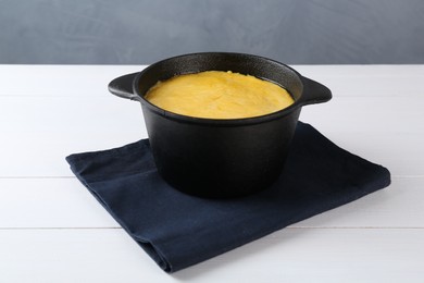 Photo of Fondue with tasty melted cheese and napkin on white wooden table