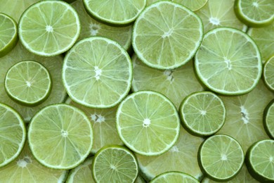 Fresh lime slices as background, top view