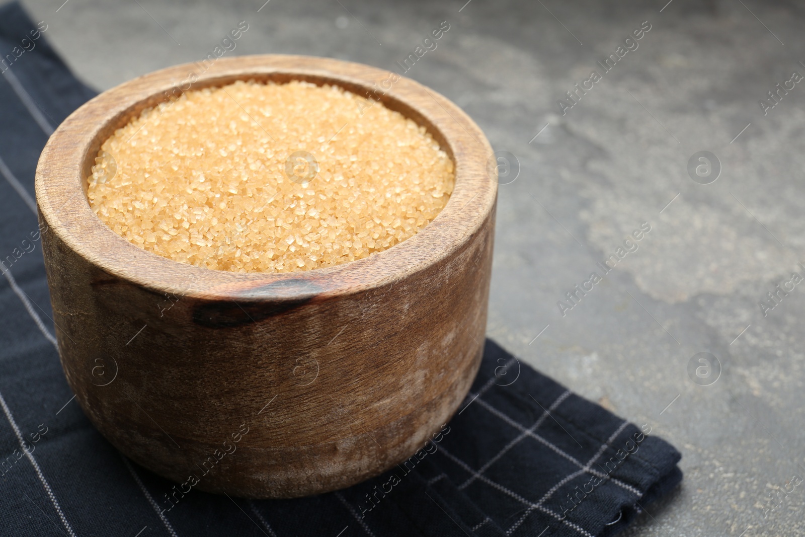 Photo of Brown sugar in bowl on grey table, closeup. Space for text