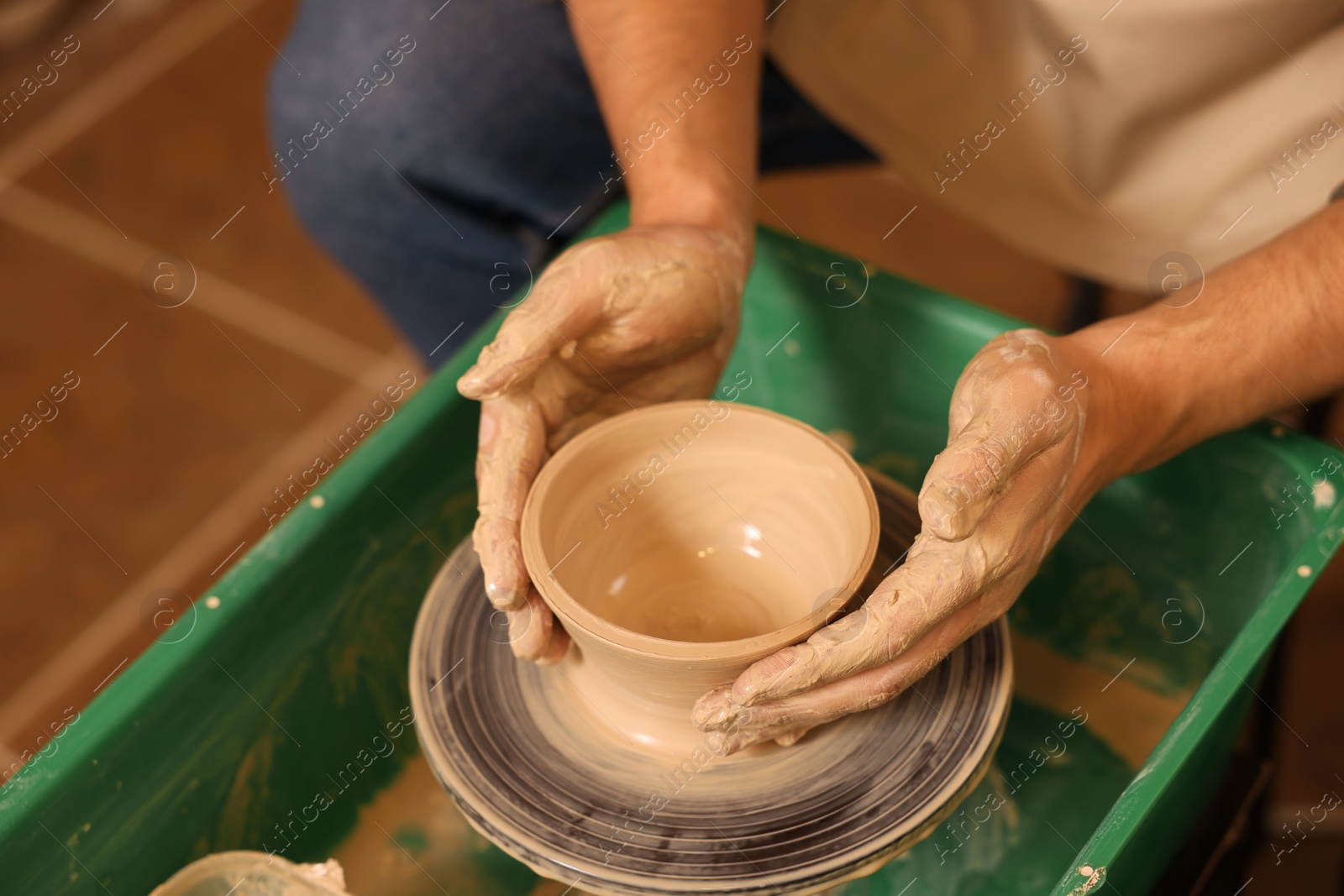 Photo of Clay crafting. Man making bowl on potter's wheel, closeup