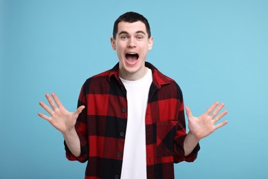 Portrait of surprised man on light blue background