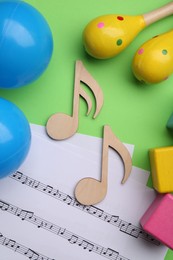 Tools for creating baby songs. Flat lay composition with wooden notes and maracas on green background