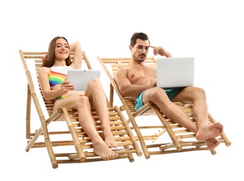 Photo of Young couple with computers on sun loungers against white background. Beach accessories