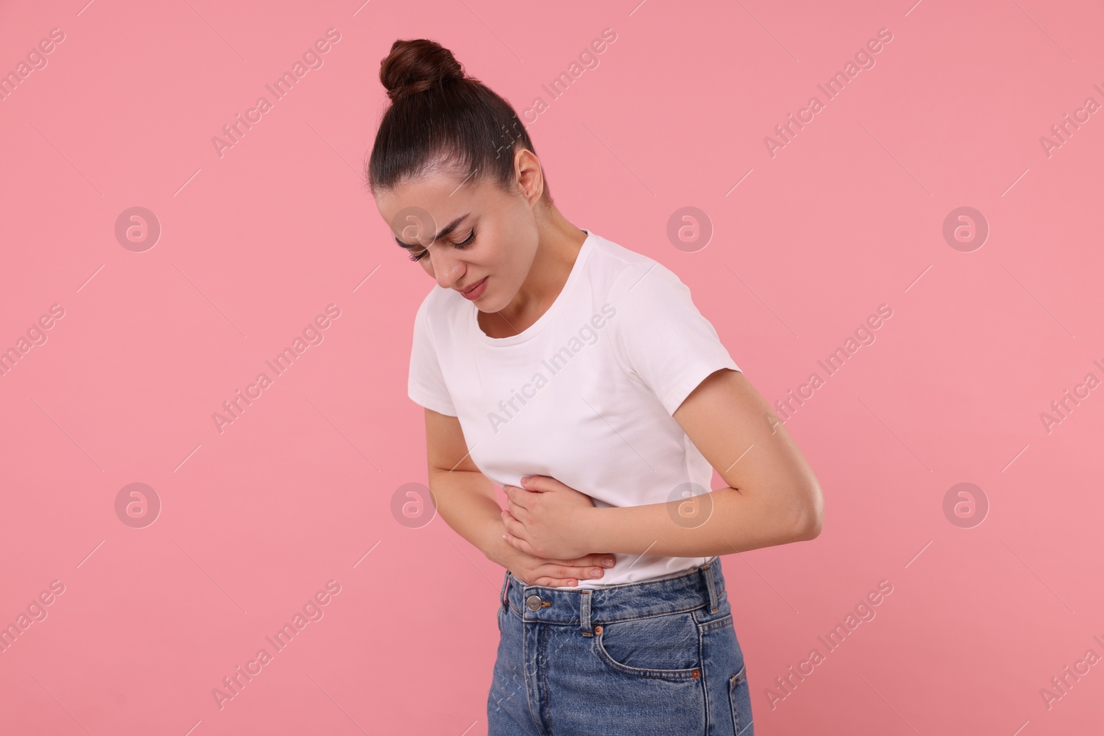 Photo of Woman suffering from abdominal pain on pink background. Unhealthy stomach