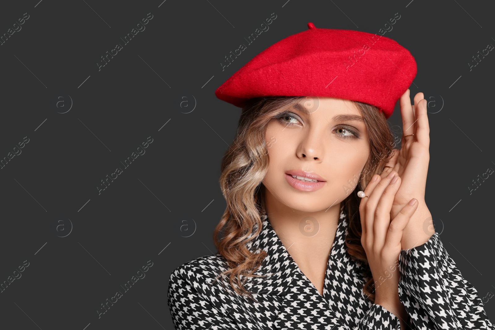 Photo of Young woman with beautiful makeup in red beret against black background. Space for text