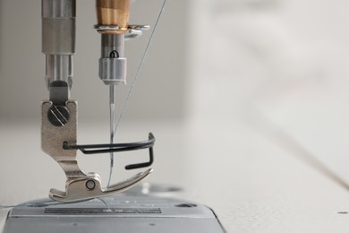Photo of Modern sewing machine on blurred background, closeup. Space for text