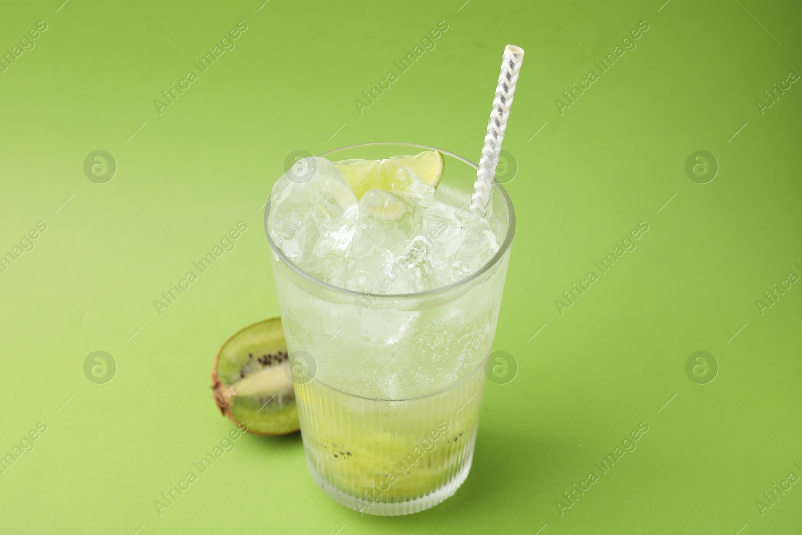 Photo of Glass of refreshing drink and cut kiwi on green background