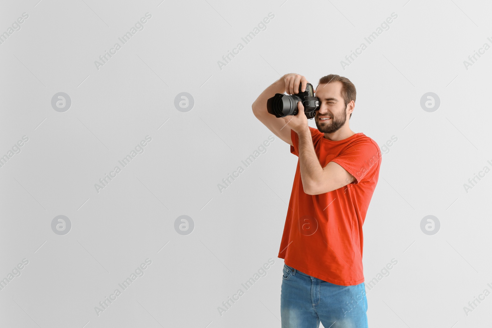 Photo of Young photographer with professional camera on white background