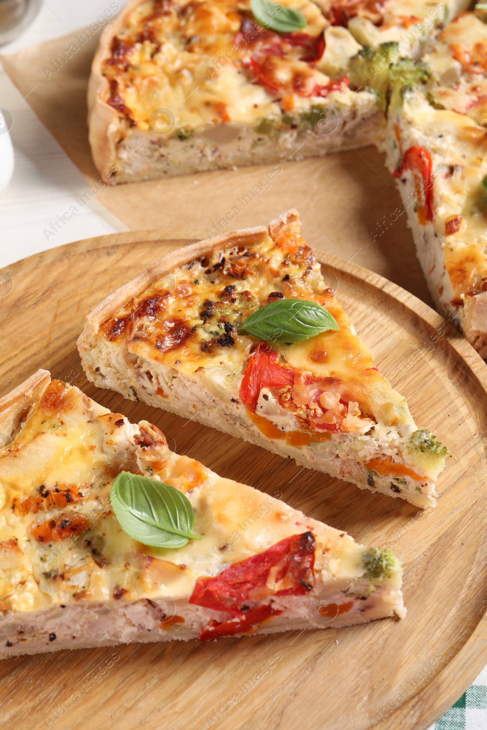 Photo of Tasty quiche with chicken, vegetables, basil and cheese on white table, closeup