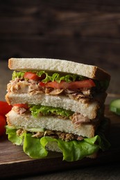Photo of Delicious sandwich with tuna, tomatoes and lettuce on wooden table, closeup