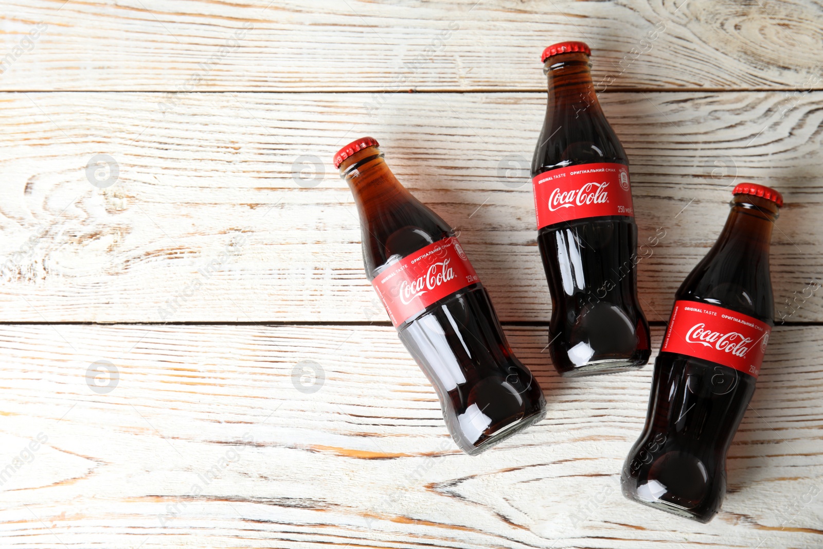 Photo of MYKOLAIV, UKRAINE - NOVEMBER 15, 2018: Bottles of Coca Cola on wooden background, top view. Space for text