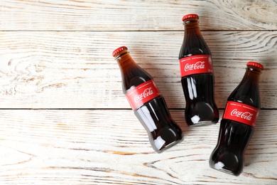 MYKOLAIV, UKRAINE - NOVEMBER 15, 2018: Bottles of Coca Cola on wooden background, top view. Space for text