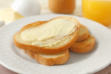 Photo of Tasty bread with butter on white plate, closeup