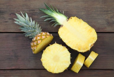 Cut ripe pineapples on wooden table, flat lay
