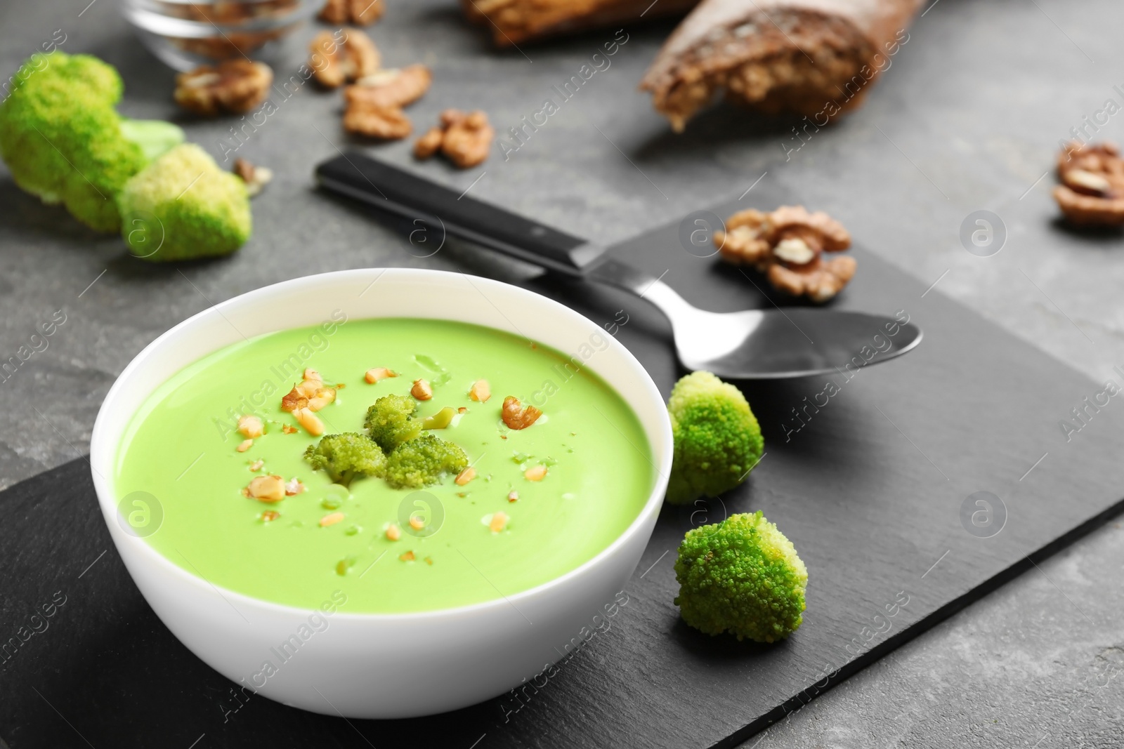 Photo of Bowl of cheese cream soup with broccoli served on grey table